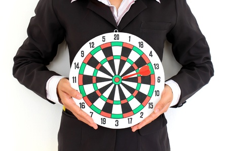 Businesswoman in a suit holds a dart boardの写真素材