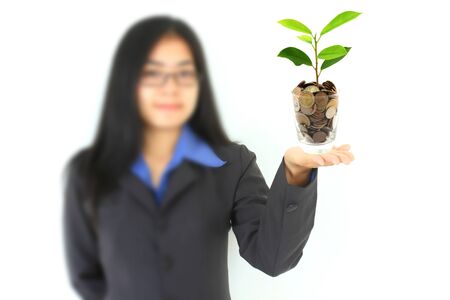 pretty young businesswoman holding a growing plant and coins (Select Focus)の写真素材