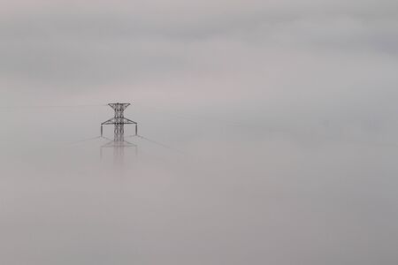 Electrical power lines and pylons emerging from the mistの写真素材