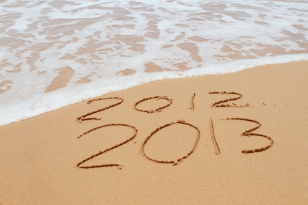 2013 year on the sand beach near the ocean. 2012 is been erasing by waveの写真素材