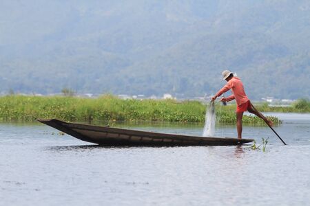 INLE LAKE, MYANMAR - NOVEMBER 18 : Fisherman catches fish for food on NOVEMBER 18, 2012 on Inle Lake, Myanmar. Intha people possess the leg-rowing style and the unique coop-like fishing equipmentのeditorial素材