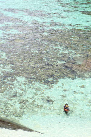 Young man   over coral reef in transparent tropical seaの写真素材