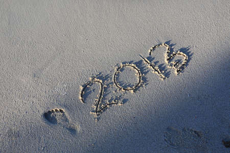 New Year 2014 season is coming concept - inscription 2013 and 2014 on a beach sandの写真素材