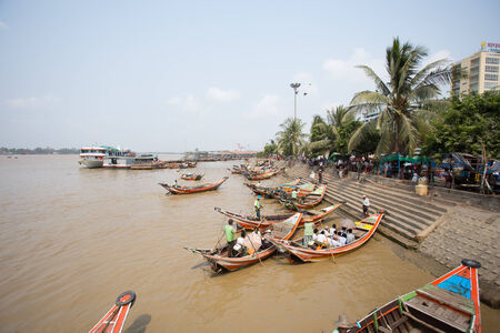 Yangon, Myanmar - April 6, 2014: A man navigates his boat full of passengers out of the busy Yangon port, Yangon is the largest city of Myanmar and the Port of Yangon is the country's most import portのeditorial素材