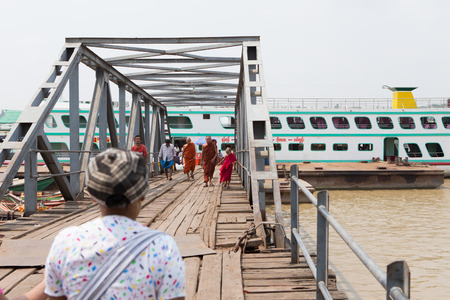 Yangon, Myanmar - April 6, 2014: A man navigates his boat full of passengers out of the busy Yangon port, Yangon is the largest city of Myanmar and the Port of Yangon is the country's most import portのeditorial素材