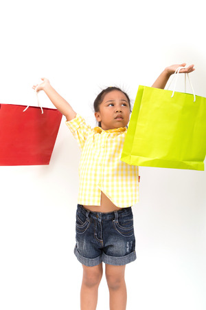Portrait of a little fashion shopping girl with shopping bags, isolated over whiteの写真素材