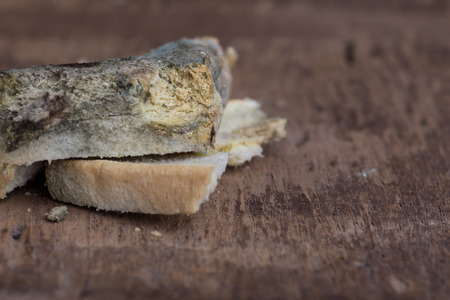Mouldy bread on cutting board, on wooden backgroundの写真素材