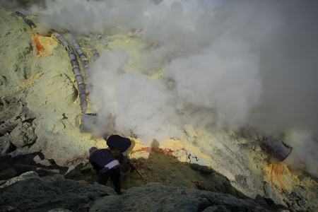 KAWAH IJEN, INDONESIA - OCT 12: Worker at sulfur mine inside Ijen crater on October 12, 2015. Miners are extracting gaseous sulfur going out in the mine of the craterのeditorial素材