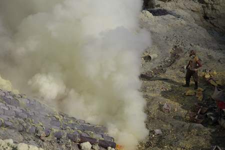 KAWAH IJEN, INDONESIA - OCT 12: Worker at sulfur mine inside Ijen crater on October 12, 2015. Miners are extracting gaseous sulfur going out in the mine of the craterのeditorial素材