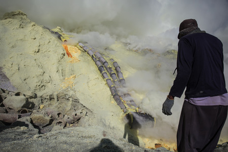 KAWAH IJEN, INDONESIA - OCT 12: Worker at sulfur mine inside Ijen crater on October 12, 2015. Miners are extracting gaseous sulfur going out in the mine of the craterのeditorial素材