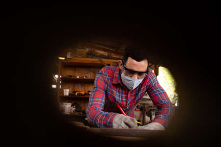 Skilled carpenter cutting a piece of wood in his woodwork workshop