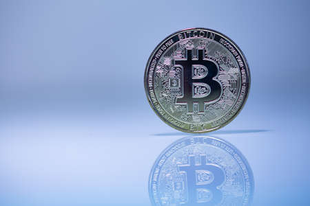 Bitcoin BTC cryptocurrency physical coin placed on the reflective surface