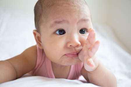 Asian cute baby in white sunny bedroom. Newborn child relaxing on bedの写真素材