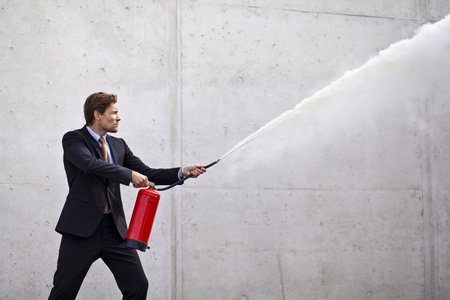 Businessman using fire extinguisher at a target as if controlling damage og problemsの写真素材