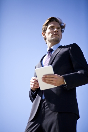Businessman holding a tablet looking into the distance or future の写真素材