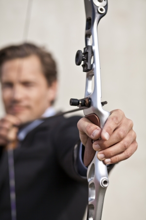 Confident businessman targeting something in the distance with his bow and arrowの写真素材