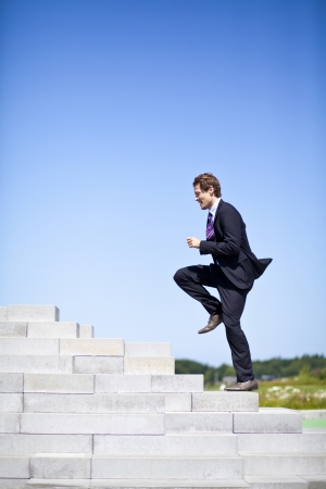 Businessman running up stairs outside  Achieving goals through challenges, showing courage の写真素材