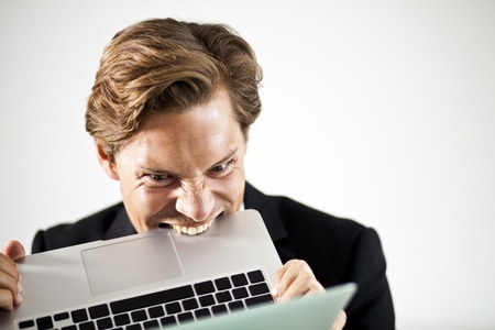 Man biting a laptop in frustrationの写真素材