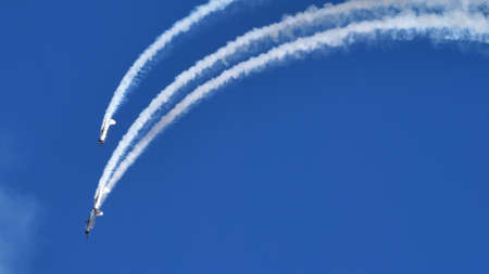 Thiene Italy OCTOBER, 16, 2021 Aircrafts paint a loop in the blue sky with white smokes during an airshow. Yakovlev Yak-52 by YAK Italiaのeditorial素材