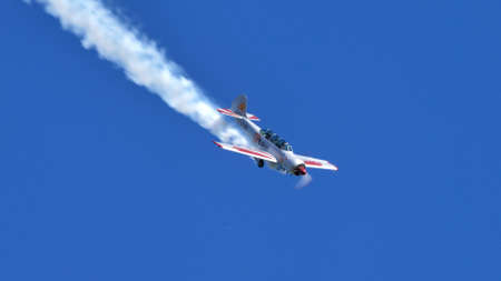 Thiene Italy OCTOBER, 16, 2021 Metallic aluminum plane with smoke descending in the blue sky. Copy Space. Yakovlev Yak-52 by YAK Italiaのeditorial素材