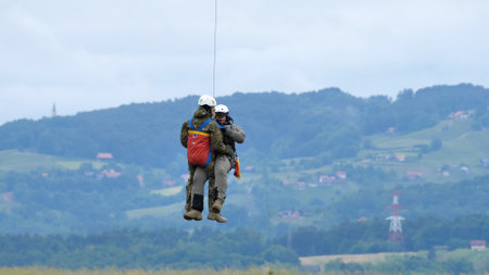 Cerklje ob Krki Slovenia MAY 29, 2022 Air rescuers dropped from a hovering helicopter to rescue people in emergency in the rain. Bell 412 of Slovenian Air Force. Copy Spaceのeditorial素材