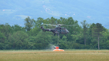 Cerklje Slovenia MAY 29, 2022 Fire helicopter fills the bambi bucket with water while hovering over a tank. Eurocopter AS532 Cougar, Airbus Helicopters H215M, of Slovenian Air Force. Copy spaceのeditorial素材