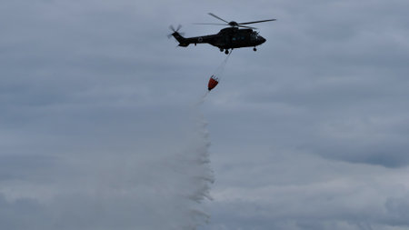 Cerklje Slovenia MAY 29, 2022 Fire helicopter opens the bucket valve and releases the water over the fire. Eurocopter AS532 Cougar, Airbus Helicopters H215M, of Slovenian Air Force. Copy spaceのeditorial素材