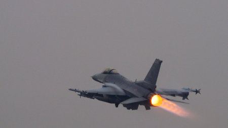 USAF fighter jet ignites its afterburner to full thrust at takeoff, the bright flame contrasting sharply against the grey sky. Ideal for editorial content. Copy space.のeditorial素材