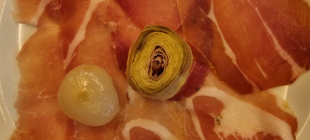Close-up of a charcuterie plate with sliced meats and pickled vegetablesの写真素材