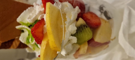 Close-up of a waffle cone overflowing with fresh fruit and scoops of rich ice creamの写真素材