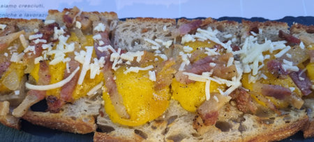 Close-up of a sandwich with crispy bacon, fried egg, and shredded cheeseの写真素材