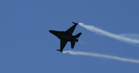 Mollis Switzerland August 19 2023: Combat aircraft executes a high speed turn, creating vapor trails from wingtips against clear blue sky during airshow. F-16 Viper of Belgian Air Force. Copy Spaceのeditorial素材