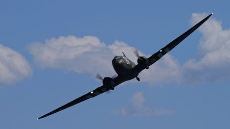 APPENZELL, SWITZERLAND - MAY 31, 2025: WWII D Day tribute Douglas C-47 Skytrain military transport aircraft banking flyby, copy space clouds behind.のeditorial素材