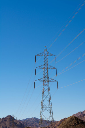 Electric support of high voltage power cables. Metal support with high voltage insulators and against the blue sky in the desert with hills and mountains.の写真素材