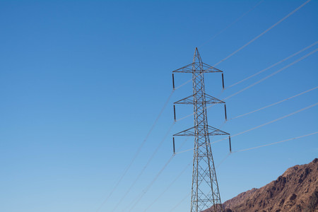 Electric support of high voltage power cables. Metal support with high voltage insulators and against the blue sky in the desert with hills and mountains.の写真素材