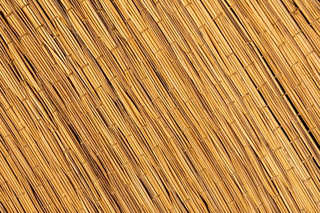 Woven straw texture. Handmade woven rug. flaxen weaving yellow mesh close up image.の写真素材