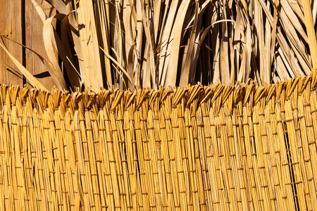 Woven straw texture with dried palm leaves on background. Handmade woven rug. flaxen weaving yellow mesh close up image.の写真素材