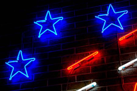 Glowing Neon blue stars on dark brick wall background. Dark tones vintage image.の写真素材