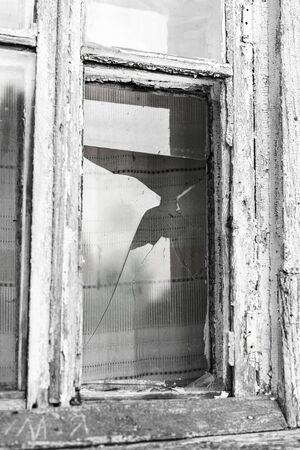 Broken Window of an old abandoned house. black and white image.