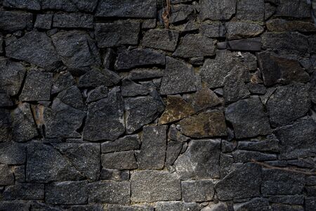stone fence. fence of black stones of irregular shape. a fence of chipped stones. stone texture.の写真素材