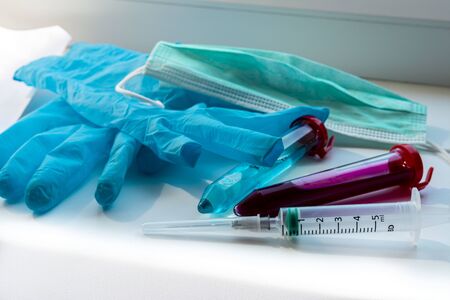 Centrifuge tubes with blue and red substance similar to a medicine or vaccine. medical glove, syringe and mask near test tubes. Theme photo: health and epidemics of the coronavirus (COVID-19)の写真素材