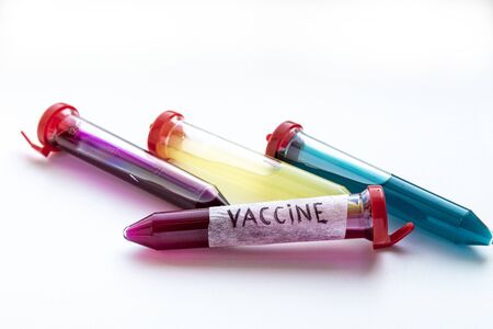 Four test tubes with red, yellow and blue liquid on a white background. On one of the test tubes is the inscription VACCINE. The substance in test tubes is similar to a vaccine for the virus COVID-19の写真素材