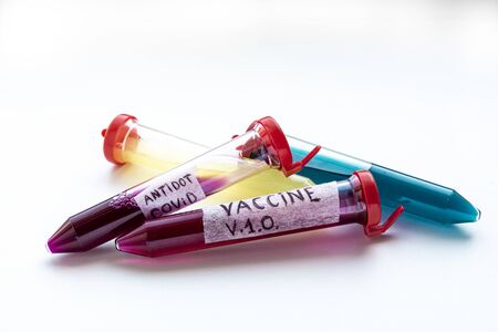 Four test tubes with red, yellow and blue liquid on a white background. On one of the test tubes is the inscription VACCINE. The substance in test tubes is similar to a vaccine for the virus COVID-19の写真素材