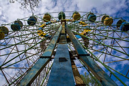 Vintage old ferris wheel in blue and yellow against the blue sky and white clouds.の写真素材