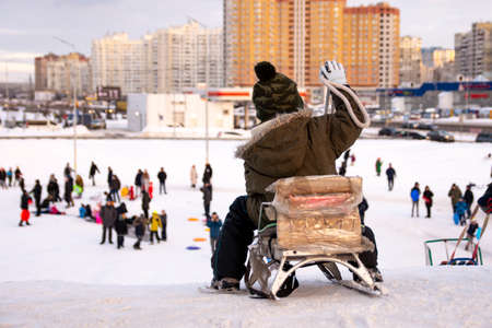 A child on a sled is about to slide down the hill.の写真素材