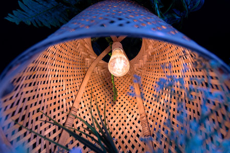 A lamp with a wicker wooden lampshade, beautiful bottom view. Cozy home atmosphere, warm light,...