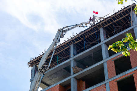 The pump delivers concrete to the roof of a high-rise building under construction. The process of...