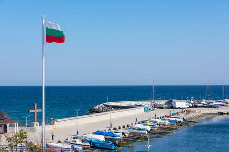 Sea pier in Bulgaria on a sunny summer day. The big flag of Bulgaria flutters in the wind.
