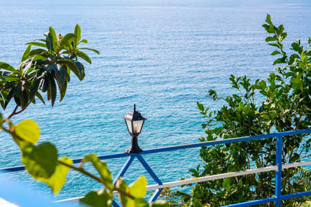 Beautiful sea view from the coastal cafe. Banana trees, rocks, lantern on the summer square above the sea.の写真素材