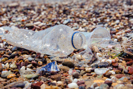 Garbage on the sea beach. A man-made garbage in the sea: plastic bottles, glasses and other plastic. Photo shows the problems of the environment due to pollution of the Earth with plastic waste.の写真素材